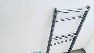 Una esquina con un estante metálico contra una pared blanca y suelo de baldosas.