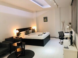 Un dormitorio moderno con una cama grande, un escritorio y una silla.