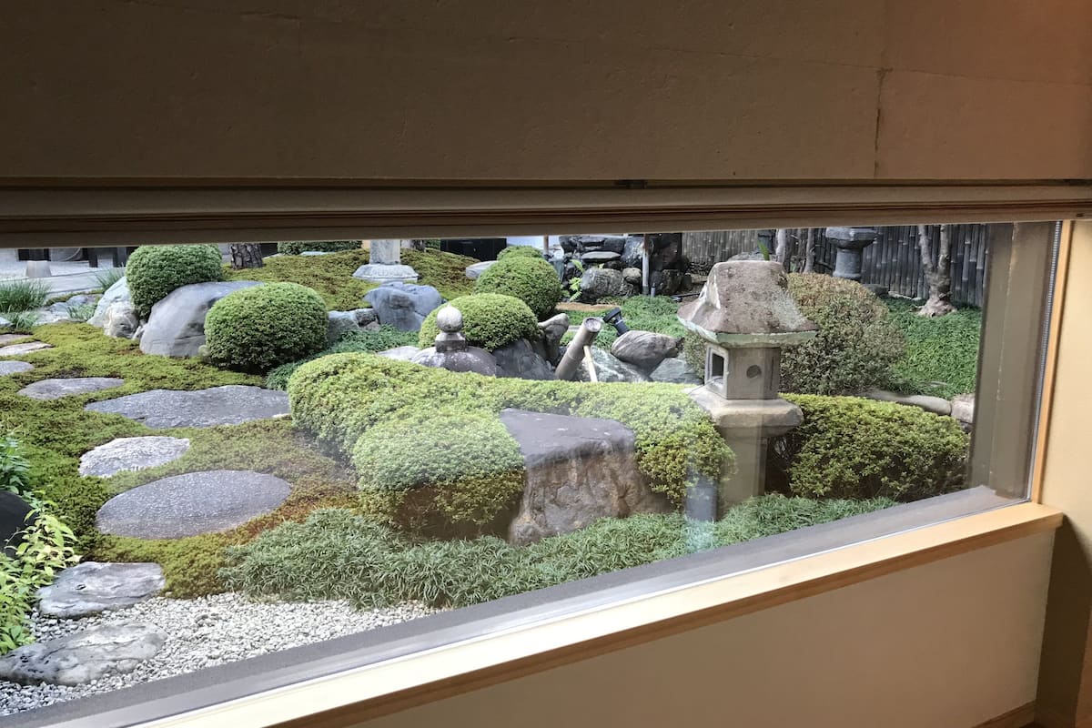 A view of a traditional Japanese garden with rocks, moss, and a stone lantern.