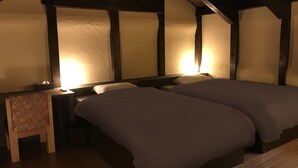 Ein gemütliches Zimmer mit zwei Betten, einem kleinen Tisch und einem Stuhl.