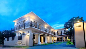Un hôtel moderne à deux étages, doté d’un balcon, de grandes fenêtres et d’une entrée bien éclairée.