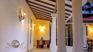 Un couloir avec des colonnes blanches, un comptoir d’accueil et des lampes fixées au mur.