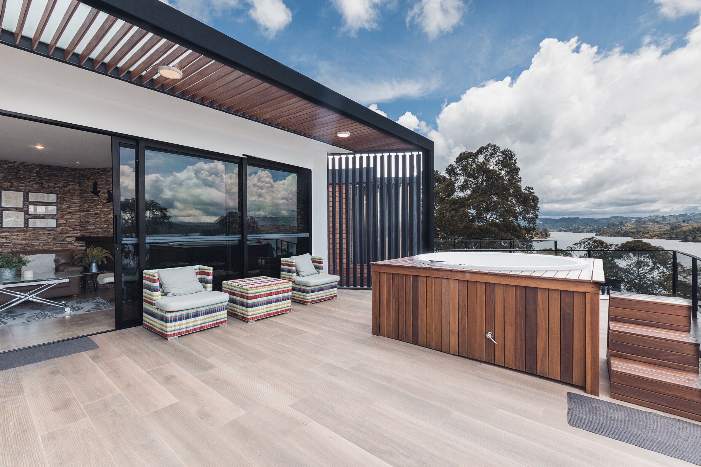 A modern outdoor living area with a hot tub, seating, and a view of the landscape.