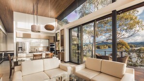 A modern interior with a glass dining table, beige sofas, and a kitchen area. - Luxé Cabañas (Guatapé)