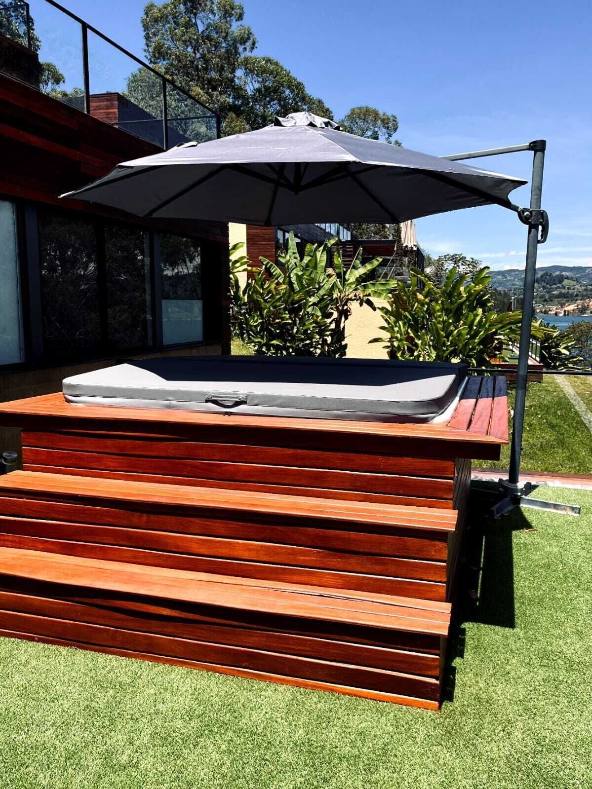 Un jacuzzi con una terraza de madera y un paraguas grande.