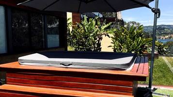Un jacuzzi con una terraza de madera y un paraguas grande.