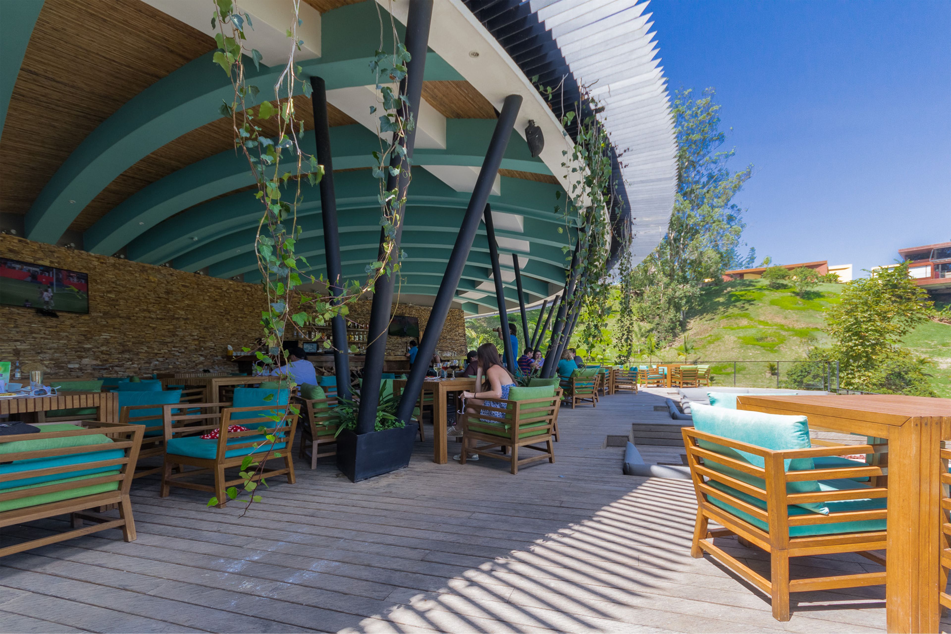 An outdoor dining area with wooden furniture and hanging plants.