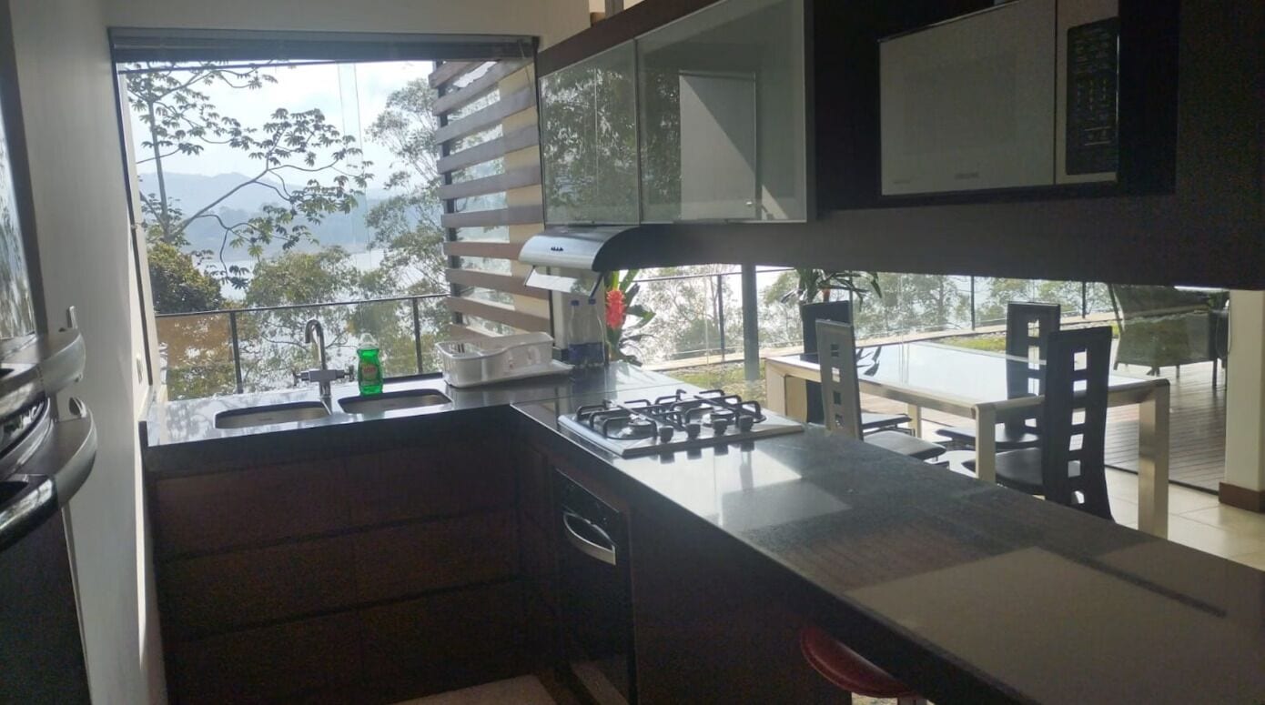 A kitchen with a gas stove, a sink, and a window overlooking a balcony.