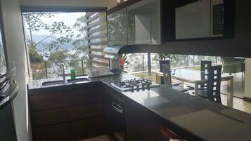 A kitchen with a gas stove, a sink, and a window overlooking a balcony.