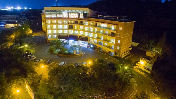 A multi-story hotel with a central courtyard, surrounded by trees and a parking area. - Ilsung Gyeongju Condominium Resort (Gyeongju)