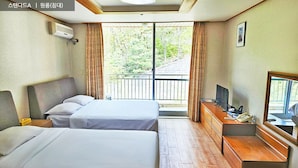 A hotel room with two beds, a desk with a telephone, a television, and a balcony with curtains. - Ilsung Gyeongju Condominium Resort (Gyeongju)