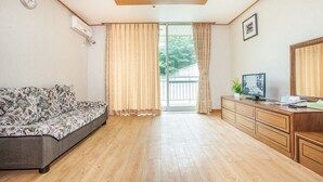 A room with a sofa, a wooden cabinet with a television, and a sliding glass door leading to an outdoor area. - Ilsung Gyeongju Condominium Resort (Gyeongju)