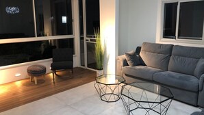 Una sala de estar moderna con un sofá gris, una mesa de centro de vidrio y una butaca.