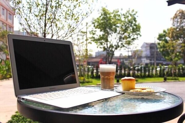 Un portátil sobre una mesa redonda de cristal, con un muffin y una taza de café.
