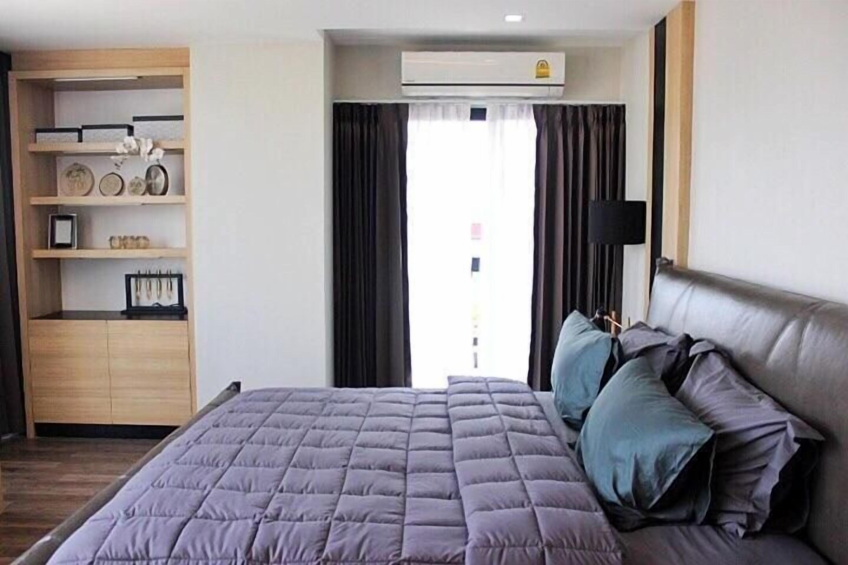 Een moderne hotelkamer met een groot bed, een inbouwkast en een raam met gordijnen.
