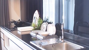 A modern kitchen with a stainless steel sink, a stove, and a dish rack with plates.