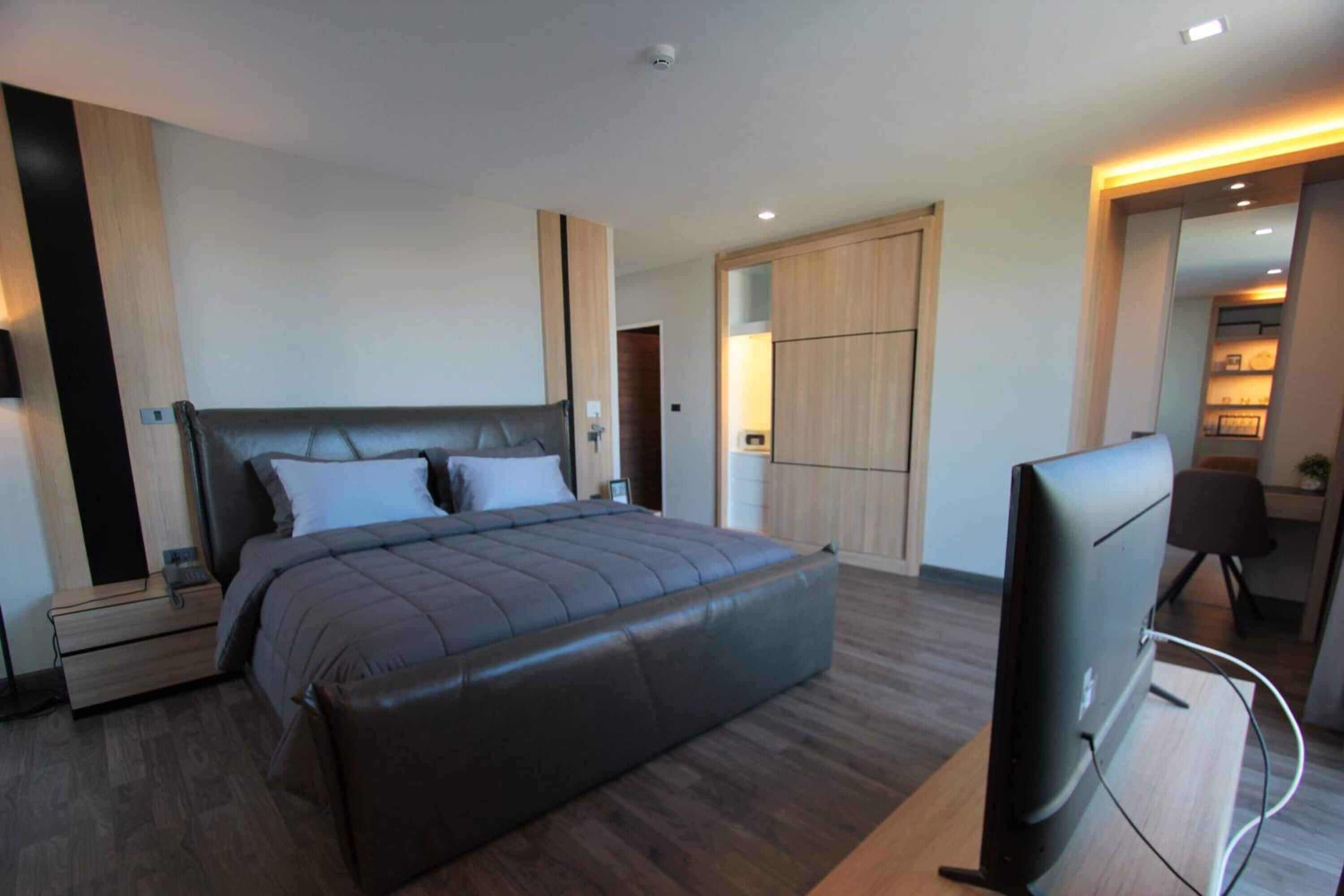 A modern bedroom with a large bed, a TV, and a wardrobe.
