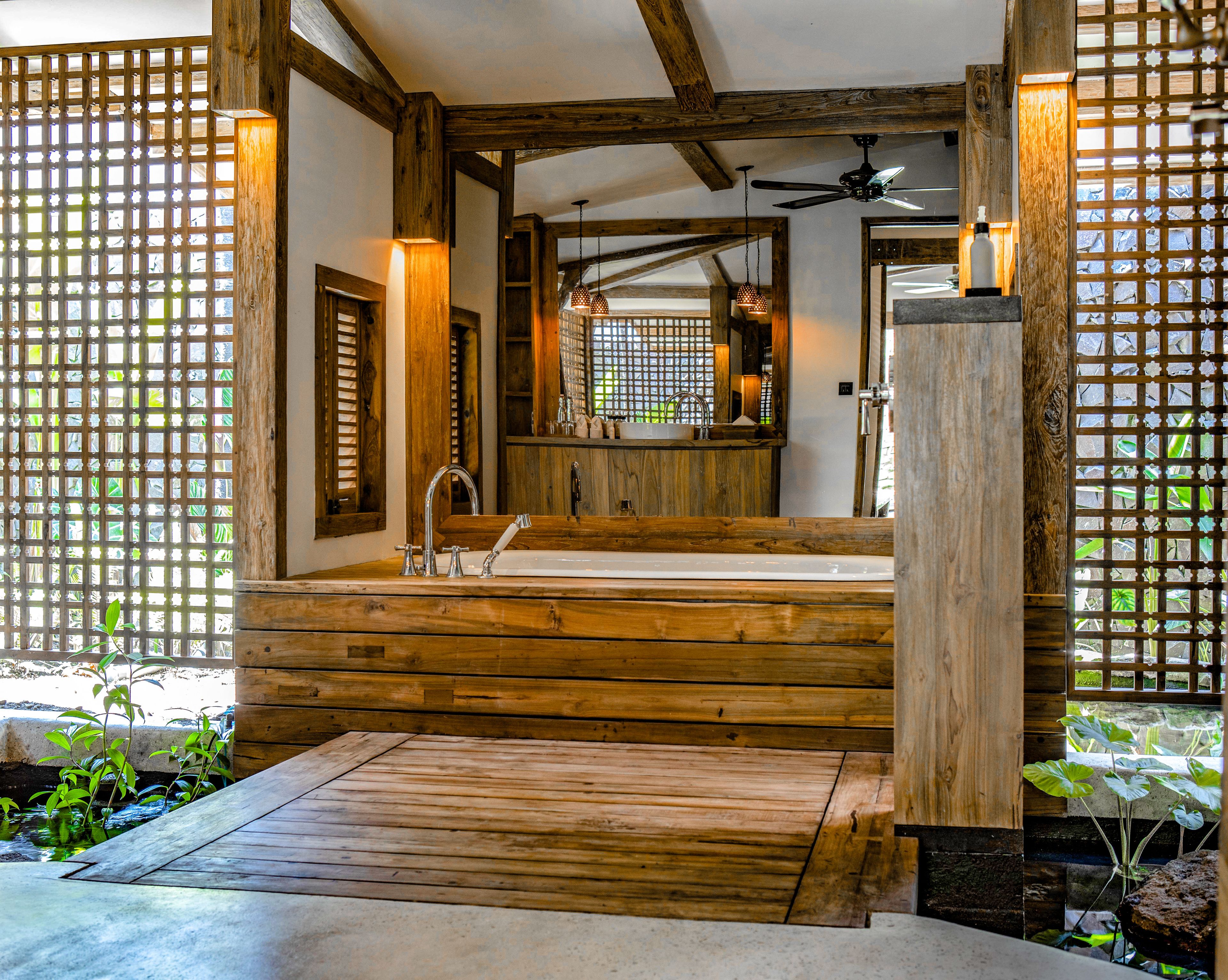 A wooden bathroom with a large sink, a ceiling fan, and a wooden floor.