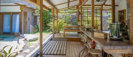 Una terraza de madera con zona de bar, piscina y vistas al jardín.