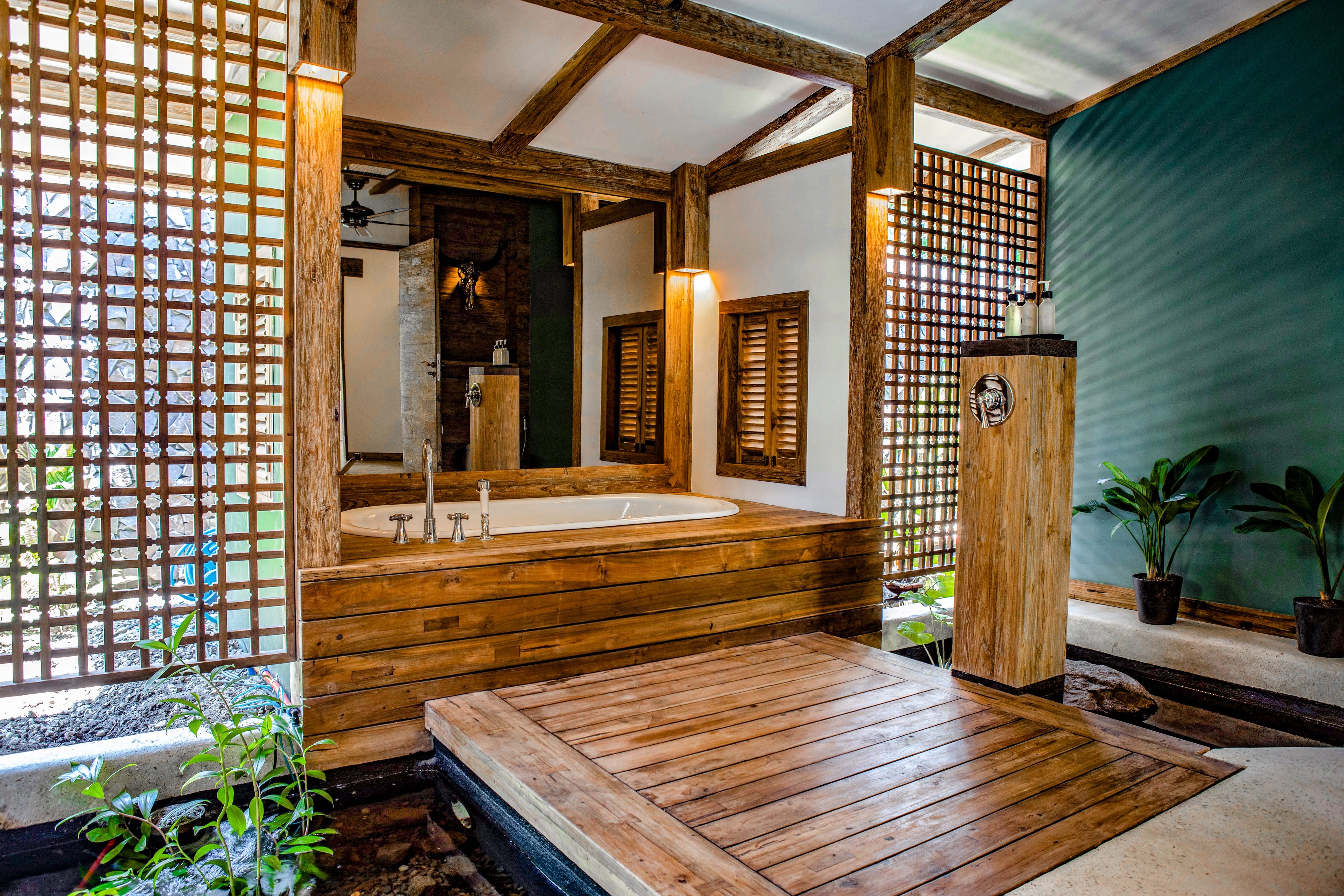 A wooden bathroom with a large bathtub, wooden beams, and a green wall.