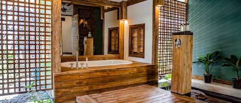 A wooden bathroom with a large bathtub, wooden beams, and a green wall.