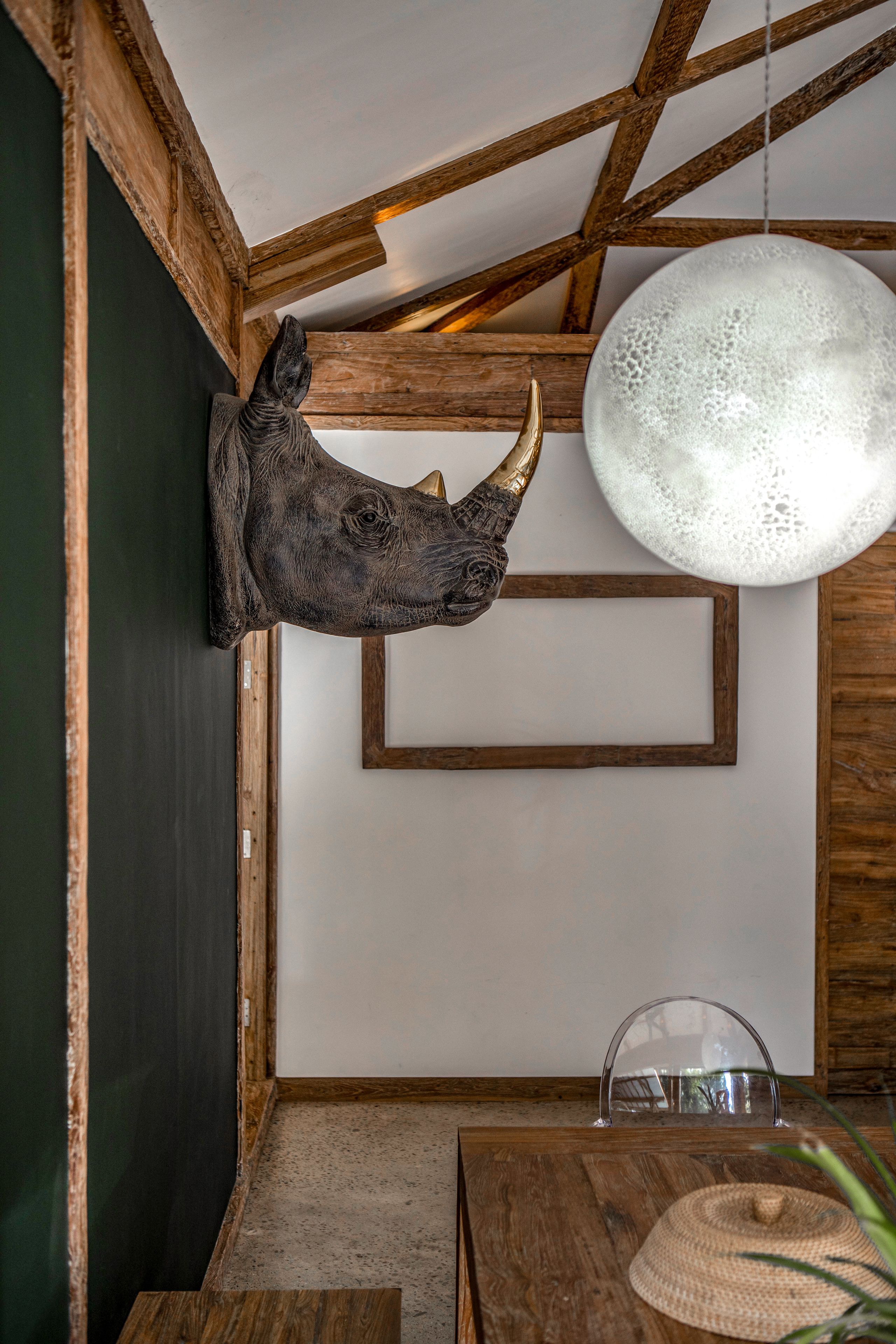Un interior rústico con un cabecero de madera, una lámpara colgante redonda y una luminaria en forma de cúpula transparente.