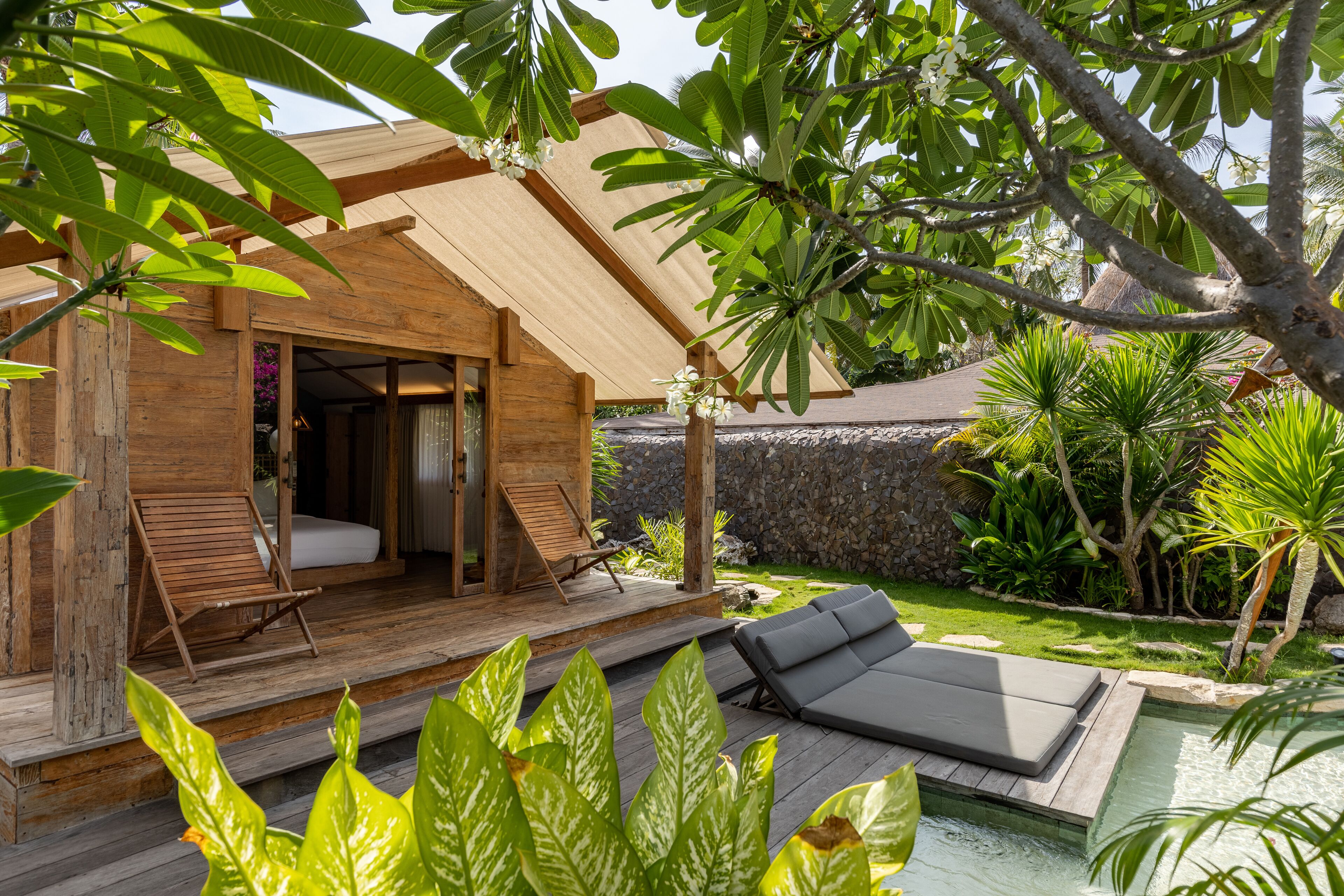 Una cabaña de madera con porche, piscina y abundante vegetación.