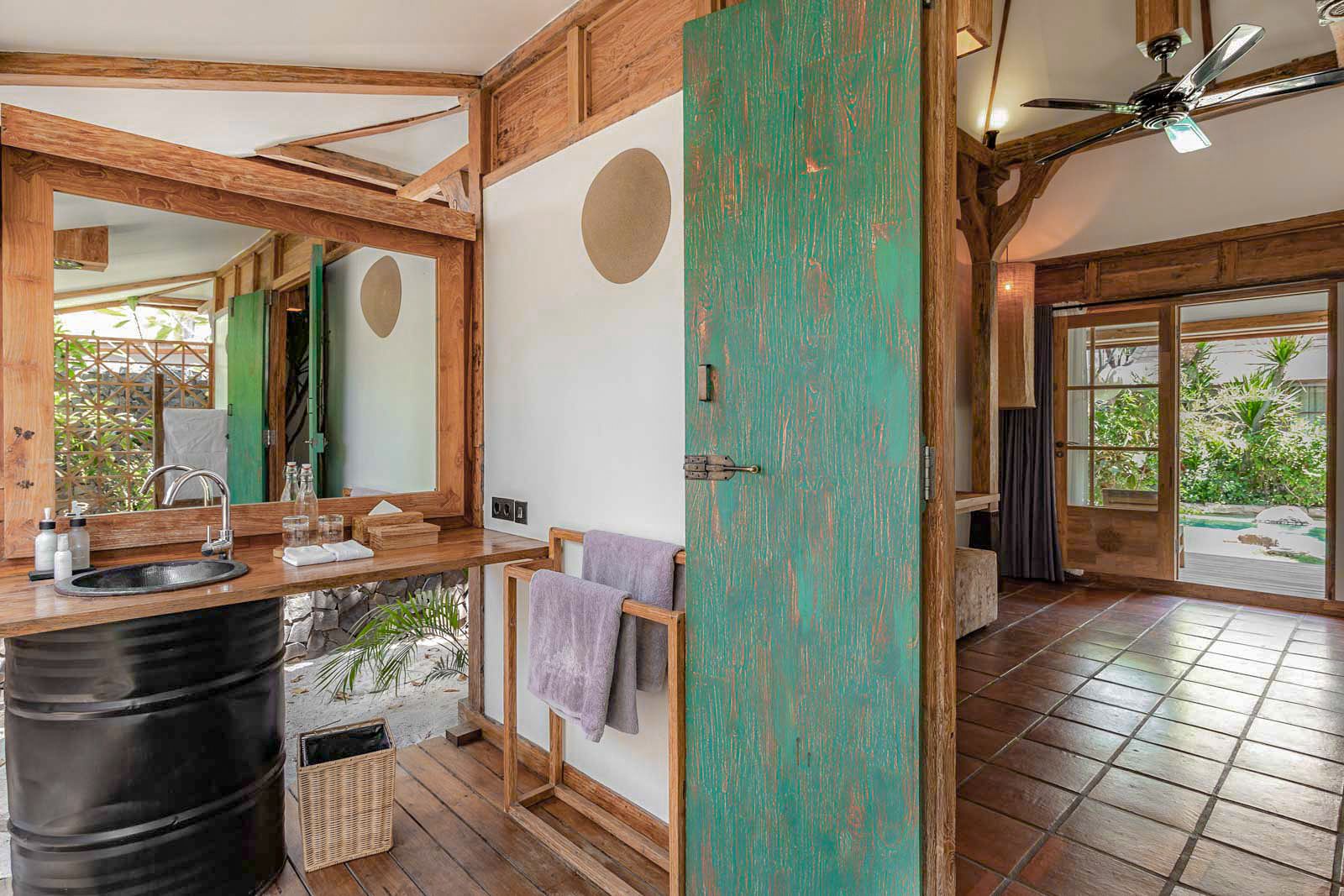 A bathroom with a wooden vanity, a sink, a mirror, and a towel rack.
