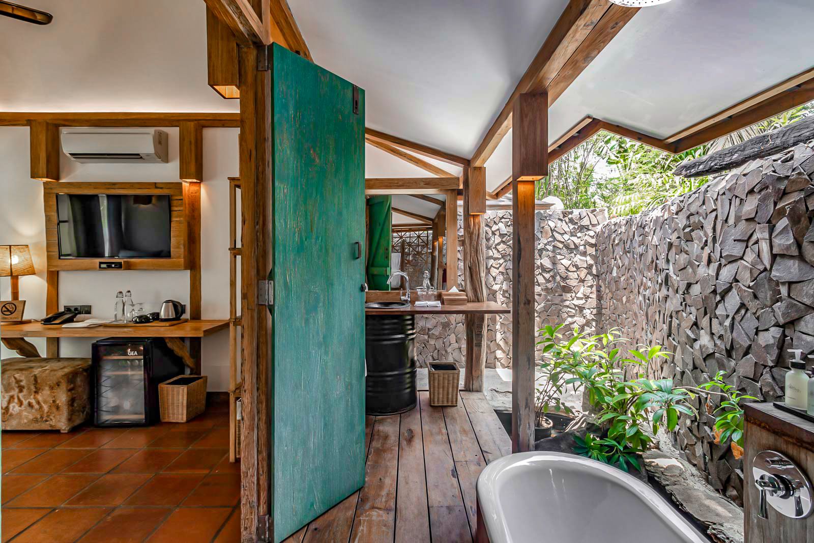 A rustic bathroom with a stone wall, wooden beams, and a bathtub.