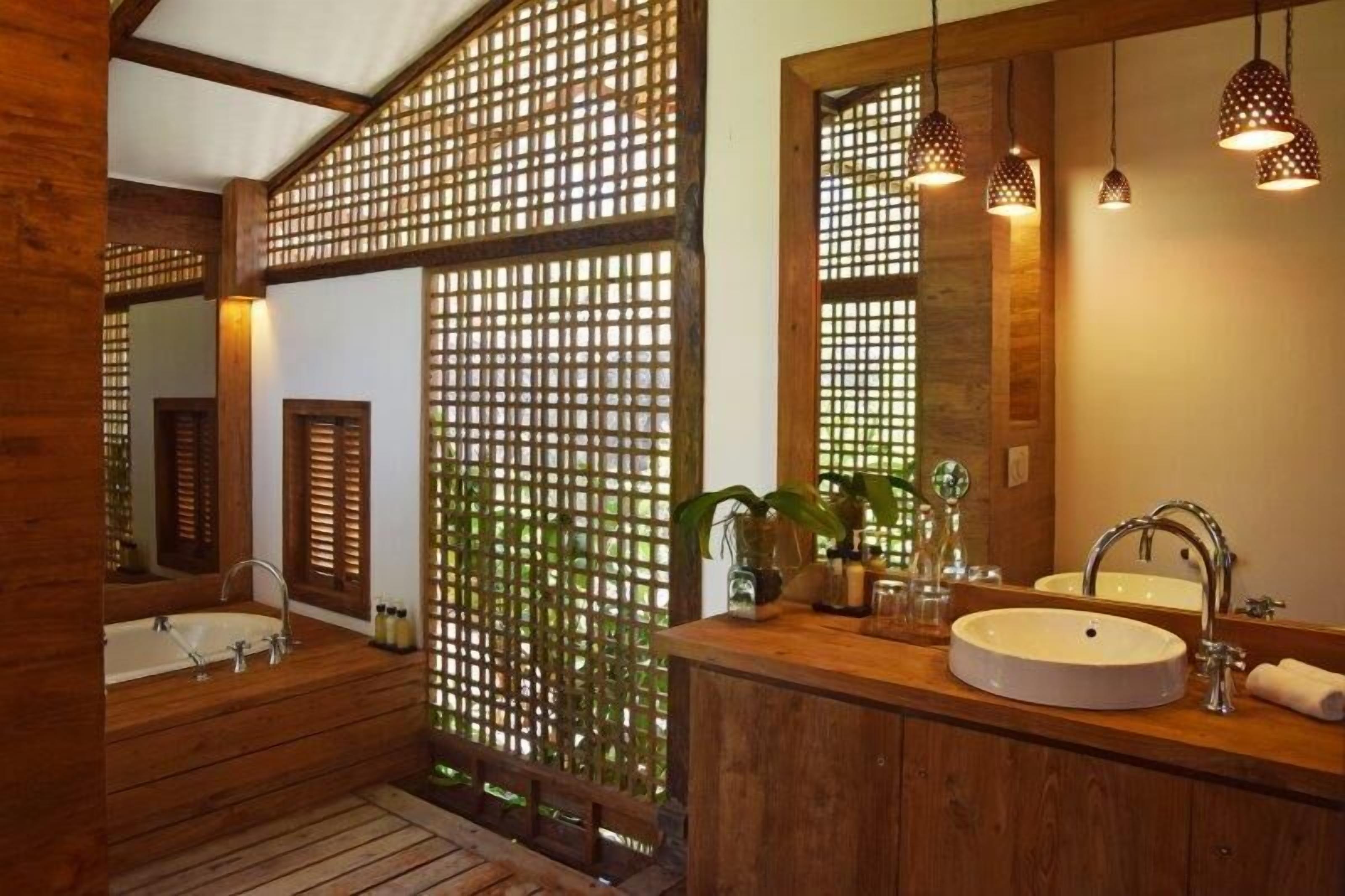 A wooden bathroom with a bathtub, a sink, and a large mirror.