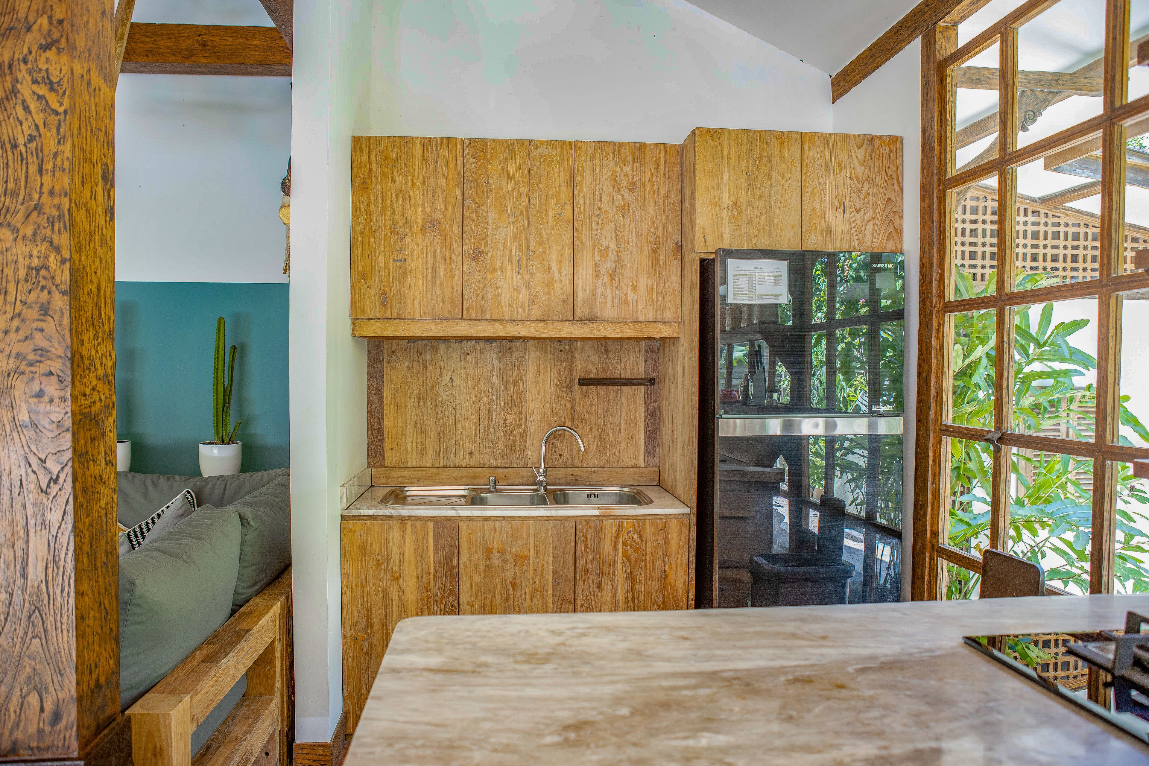 A kitchen with wooden cabinets, a sink, and a window with a view of greenery.