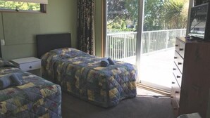 A bedroom with two beds, a dresser, and a TV.