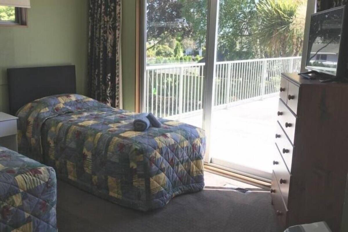 A bedroom with two beds, a dresser, and a TV.