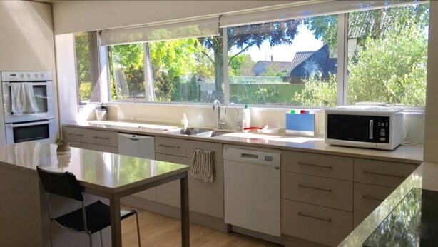 A modern kitchen with a large window, a dining table, and a microwave.