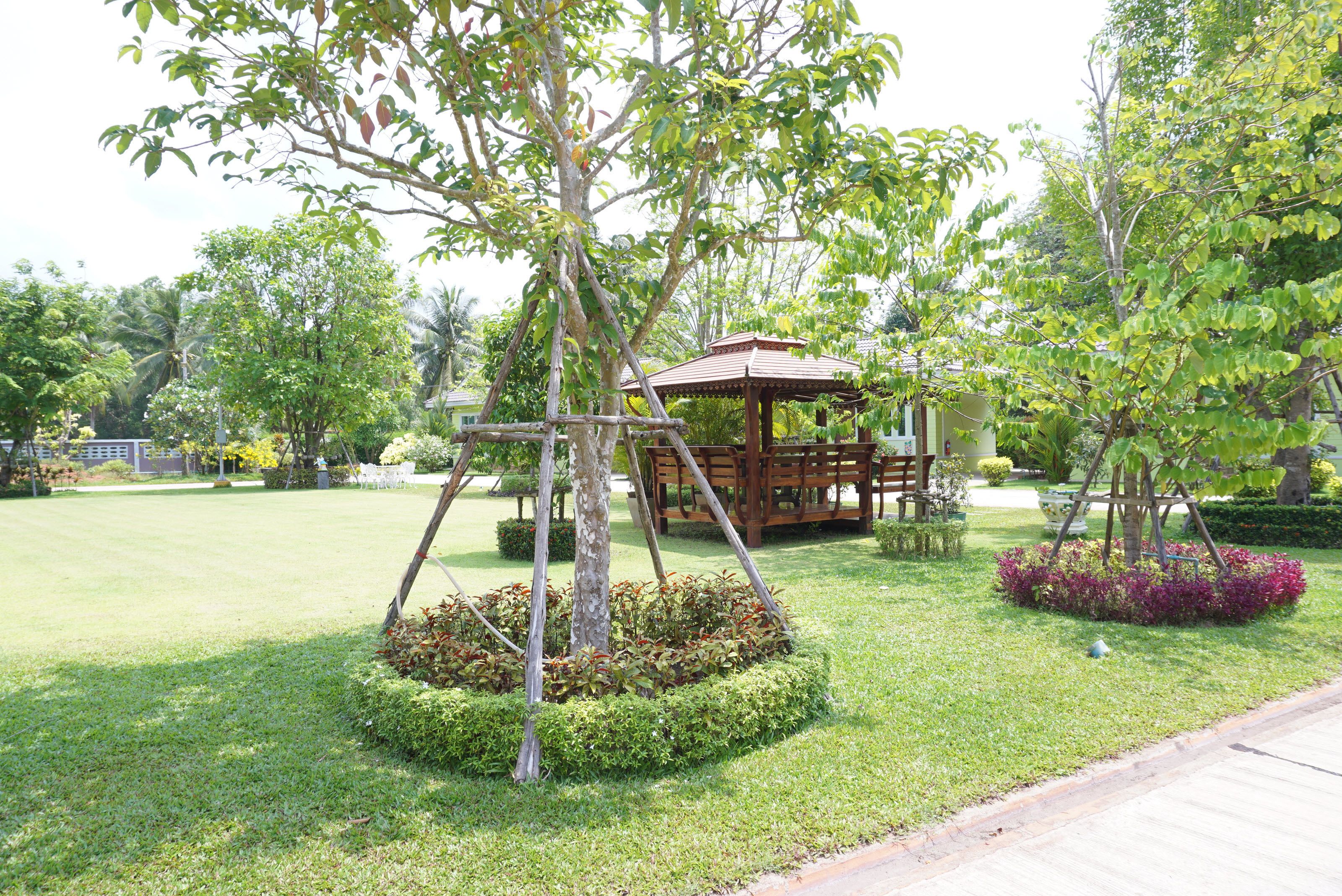 A park with a wooden swing set, a gazebo, and neatly trimmed bushes.