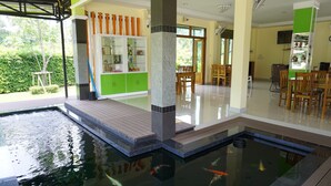A modern indoor pool with clear water, surrounded by a wooden deck and a green cabinet. - Aranya Resort (Chumphon)