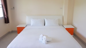 A hotel room with a large bed, white bedding, two orange nightstands, and a window with curtains. - Aranya Resort (Chumphon)