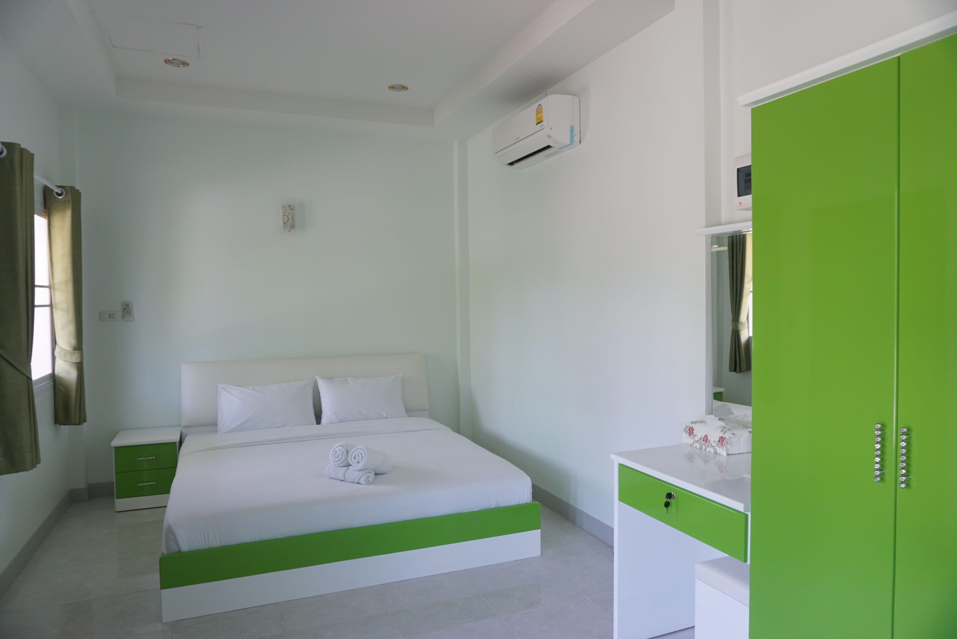 Un dormitorio con cama, mesita de noche, cómoda y equipo de aire acondicionado.