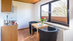 A compact kitchen with wooden cabinets, a sink, and a window with blinds.