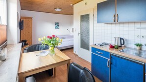 A modern kitchen with blue cabinets, a wooden dining table, and a vase of flowers.