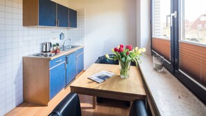 A modern kitchen with blue cabinets, a wooden table, and a vase of tulips.