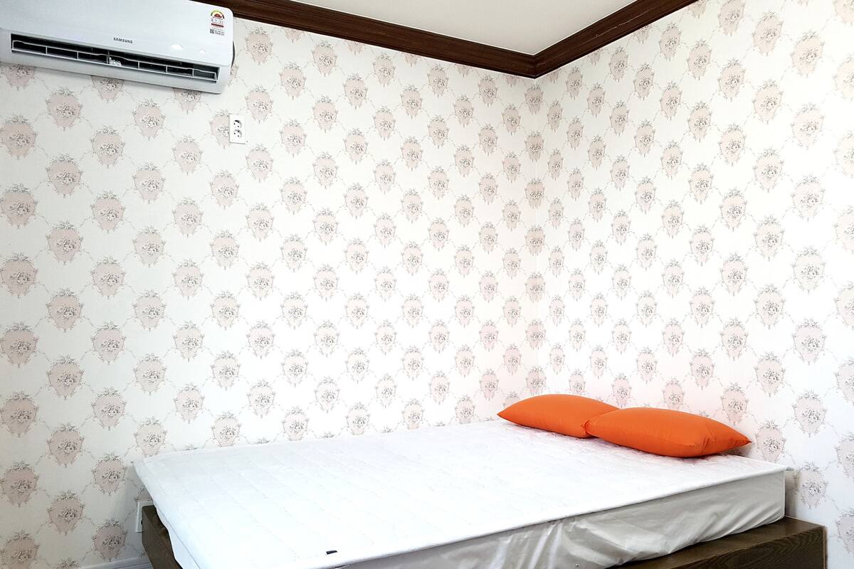 A bedroom with a bed, a wooden headboard, and a patterned wallpaper.