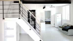 Un interior moderno con una escalera, un sofá y una zona de cocina.