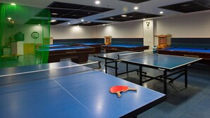 Een biljartruimte met meerdere tafels en een tafeltennistafel.