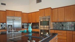 A modern kitchen with wooden cabinets, stainless steel appliances, and a black granite countertop. - Villa near Cape Harbor, with large pool, whirlpool (Cape Coral)
