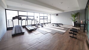 A gym with exercise equipment, large windows, and a wooden floor. - Jeju IN Hotel (Jeju City)
