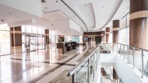A spacious lobby with a glass railing, a reception desk, and a Christmas tree. - Park Island - Bonaire by Deluxe Holiday Homes (Dubai)