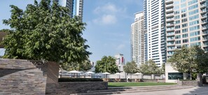 A modern urban setting with high-rise buildings, a well-maintained lawn, and outdoor seating areas.