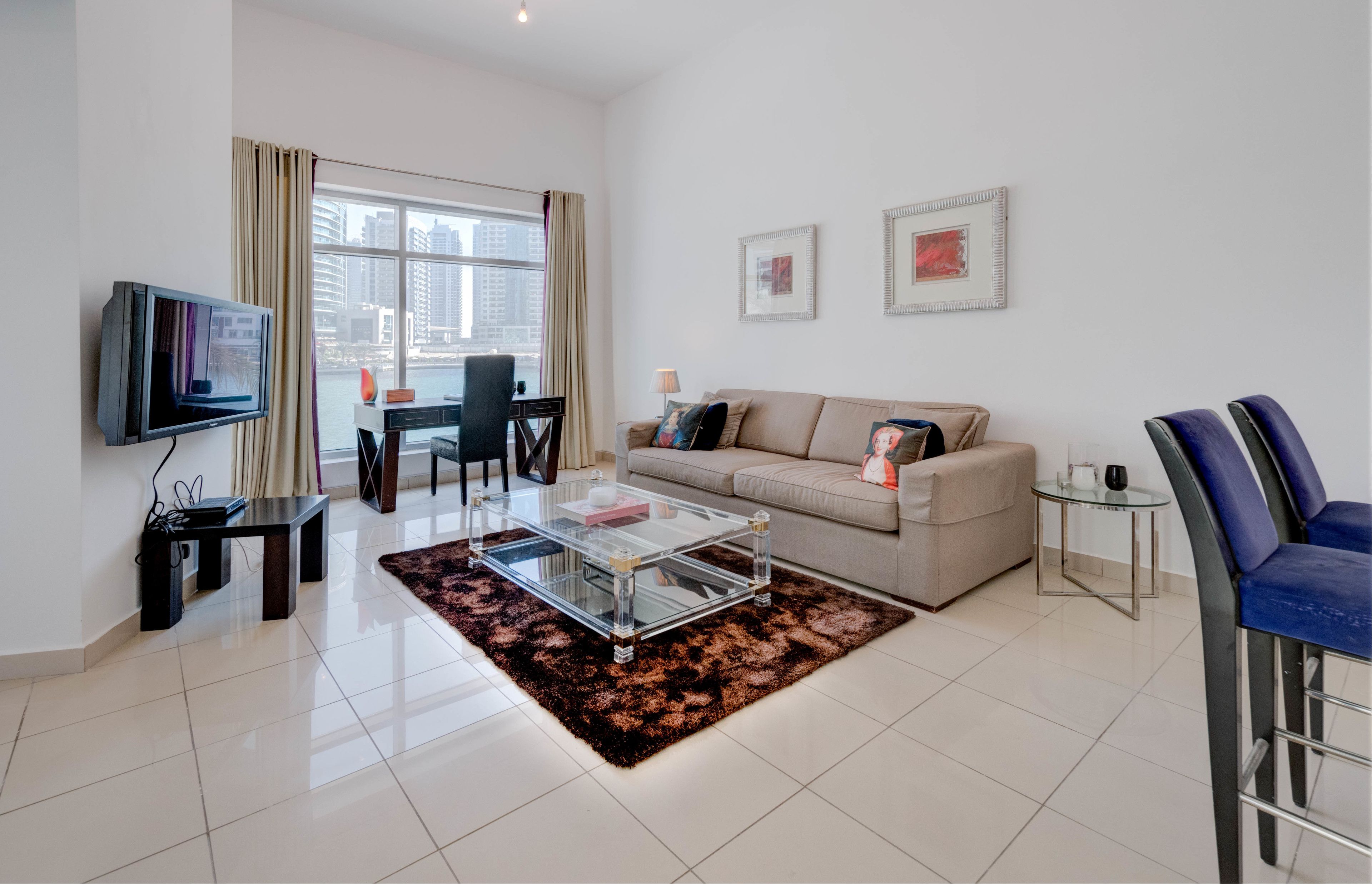 A modern living room with a sofa, coffee table, TV, and a view of the city.