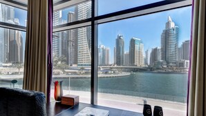 A room with a large window overlooking a cityscape with tall buildings and a river. - Park Island - Bonaire by Deluxe Holiday Homes (Dubai)